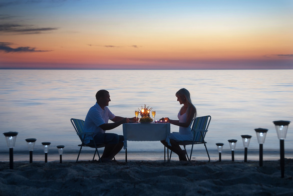 A-young-couple-share-a-romantic-dinner-with-candles-and-wine-glasses-on-the-sea-sand-beach